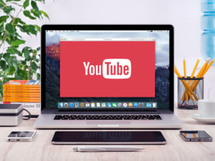An image of an Apple Mac laptop on a desktop with 'Youtube' on screen.