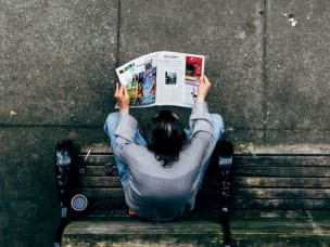 Vista di un uomo dall'alto che legge un giornale seduto su una panchina