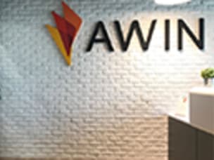 office wall made of white bricks with awin logo