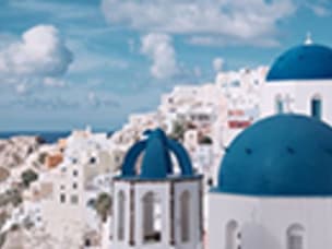 landscape with white houses and blue rooftops under a clear blue sky with puffy white clouds
