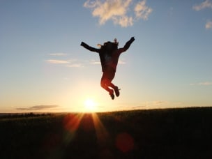 Frau macht bei Sonnenuntergang einen Luftsprung