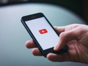 Hand hält iPhone mit YouTube Logo