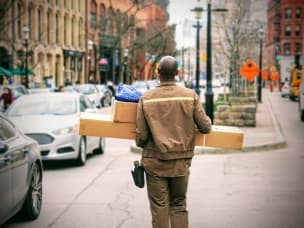 Man delivering boxes and parcels in city scape for online shopping retailer