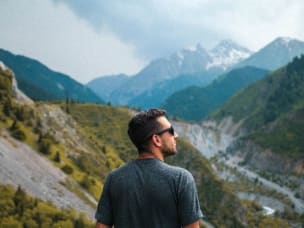 Mann mit Sonnenbrille schaut auf Berglandschaft