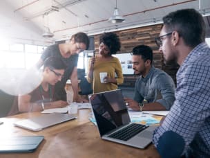 A group of coworkers gathered by the desk and working together