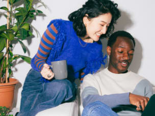 Two people leaning over a laptop screen, looking at Seán Mahon's chapter for the Awin Report 2019 on how affiliate marketing aids the conversion funnel