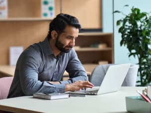 Blonde Frau sitzt mit Laptop am Tisch