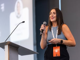 Awin speaker on stage holding a microphone at ThinkTank US 2024