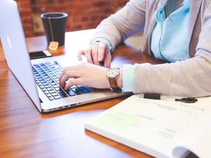 Person on their laptop, exploring Google’s attribution model, GA4, and how it impacts to measure affiliate activity
