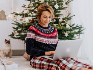 Women sitting in front of a Christmas tree, reading about Awin Talks' podcast break for the first quarter of 2024