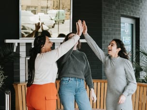A group of three people standing up and high-fiving