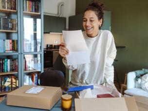 Person happily opens an online purchase, reading about donating through Savoo discount codes