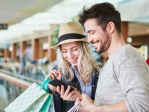 Paar im Einkaufszentrum vergleicht online mit Preisvergleichdiensten die besten Angebote im Einzelhandel