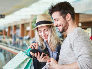 Two people checking phone while shopping