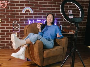 Person seated with ring light in neon setting