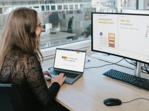 An employee working on a desktop and a laptop, both displaying the Awin website