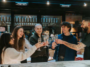 Five Awin employees raising their champagne glasses in a toast at a bar.