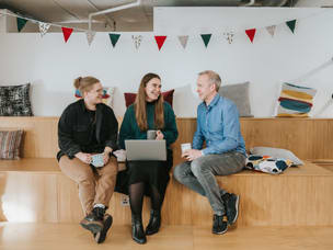 Three people sitting and talking in a casual office setting