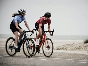 Two cyclists riding near beach