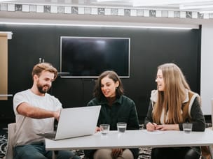 Three people discussing content on laptop