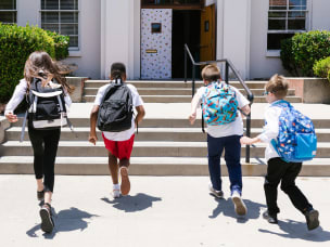 Children with backpacks entering a school building, representing education trends or youth-focused affiliate strategies.