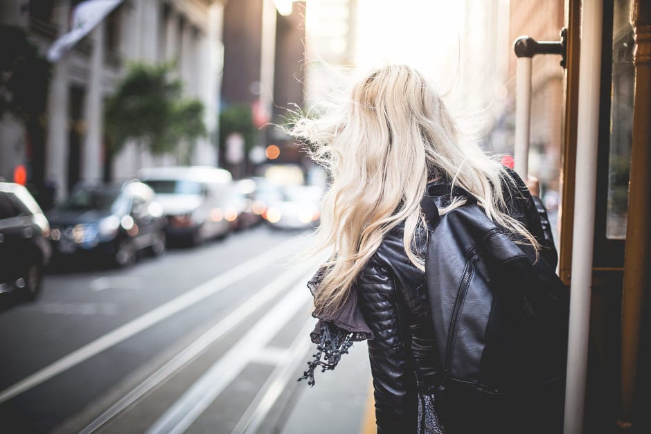 Ragazza bionda vista di spalle che scende da un tram