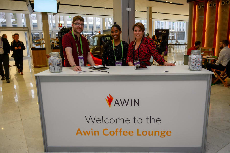 Tre membri dello staff Awin all'accoglienza dell'area lounge 