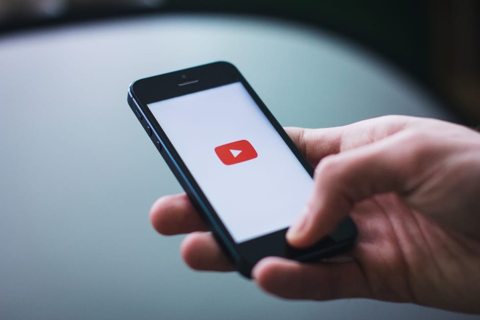 Hand hält iPhone mit YouTube Logo