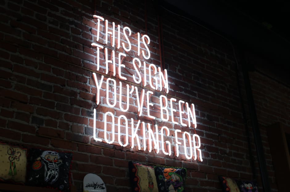 Image shows a neon sign against a brick wall, which reads ‘This is the sign you’ve been looking for’