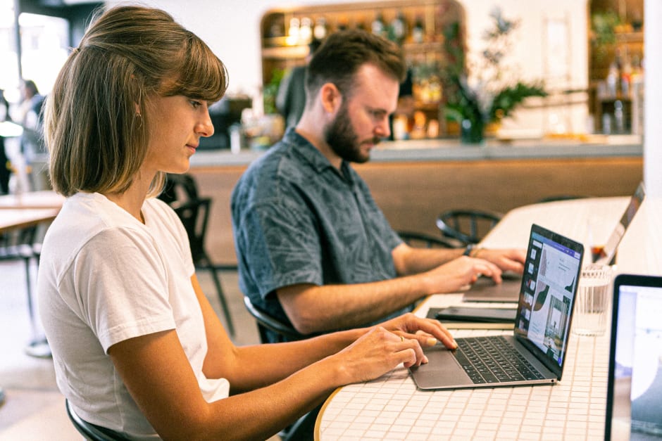 Frau und Mann sitzen mit Laptops an einem Tisch