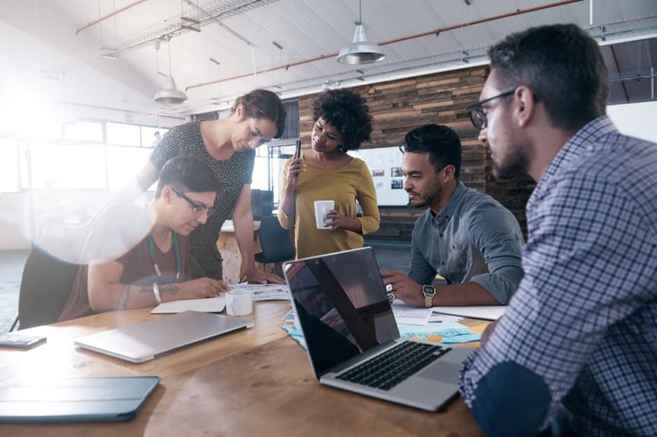 A group of coworkers gathered by the desk and working together