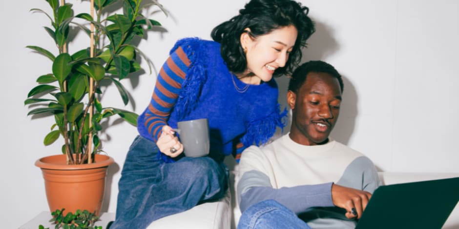 Two people leaning over a laptop screen, looking at Seán Mahon's chapter for the Awin Report 2019 on how affiliate marketing aids the conversion funne