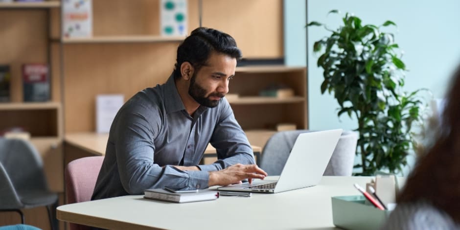 Blonde Frau sitzt mit Laptop am Tisch