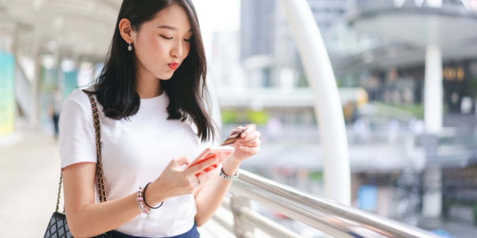 A person shopping online with a smartphone and a credit card