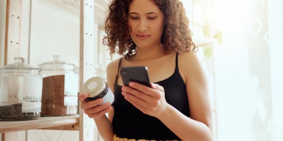 Person holding jar and phone in store
