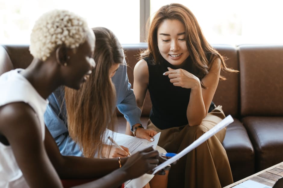 Three people sitting on a couch, collaborating and discussing documents