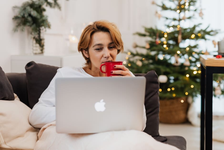 Working from home during the holiday season with a laptop by a Christmas tree.