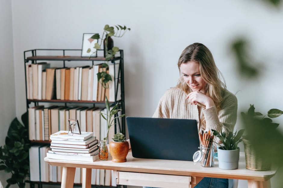 Person working at a desk with a laptop and books in a home office.
