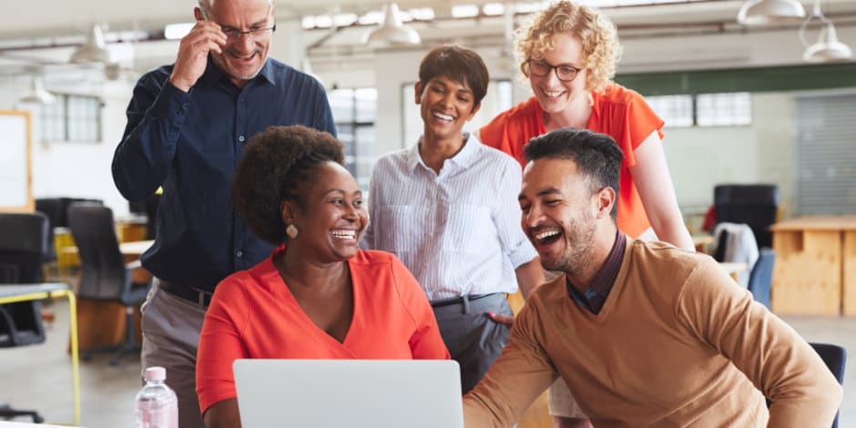Five people gathered around laptop in office