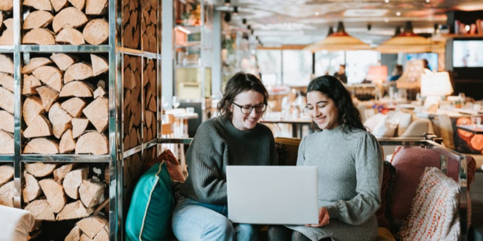 Two people, at a restaurant, sitting on a couch, using a laptop