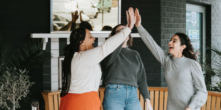 A group of three people standing up and high-fiving