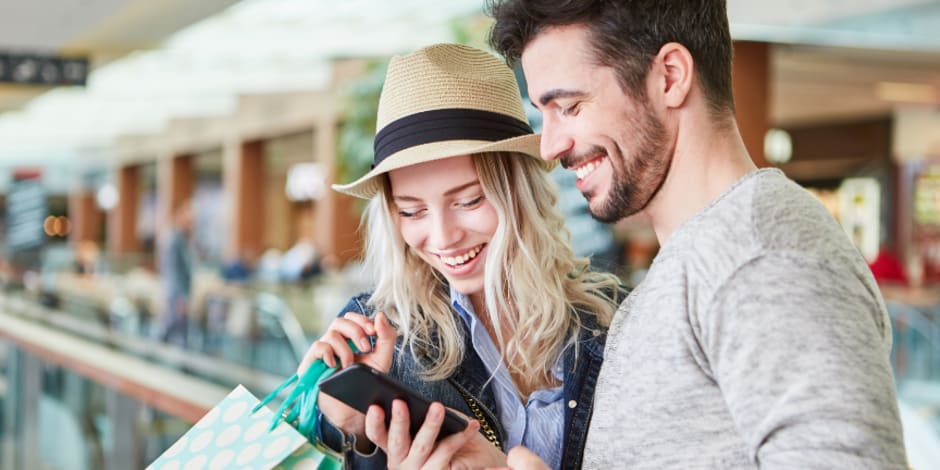 Two people checking phone while shopping