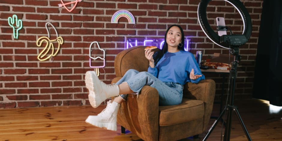 Person seated with ring light in neon setting