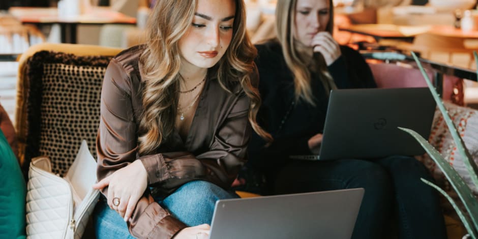Two people working on laptops in café
