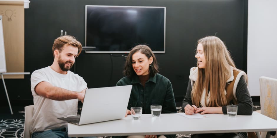 Three people discussing content on laptop