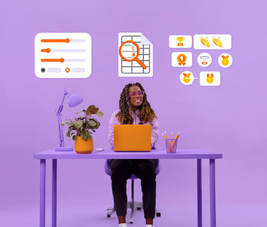 Person sitting, smilling, at a desk with a laptop in a purple setting